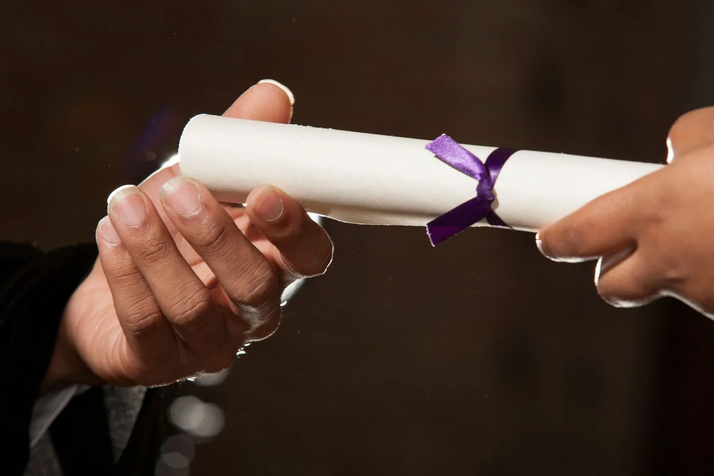 Diploma met lint wordt van hand tot hand overhandigd